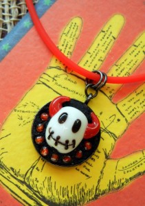 This free jewelry project by Rings & Things features a stitched devil head lampwork bead as the centerpiece of a mini mosaic. Small beads surround the black white and red focal, which is set into Encapture Artisan Concrete (jewelry grade concrete). The small mosaic is held inside an inexpensive 1" round bezel cup.